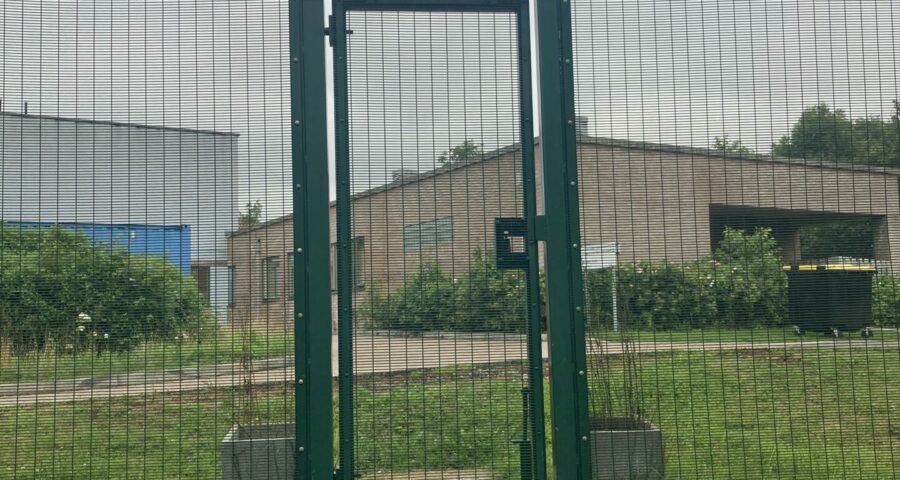 Picture of a wire fence with a locked door